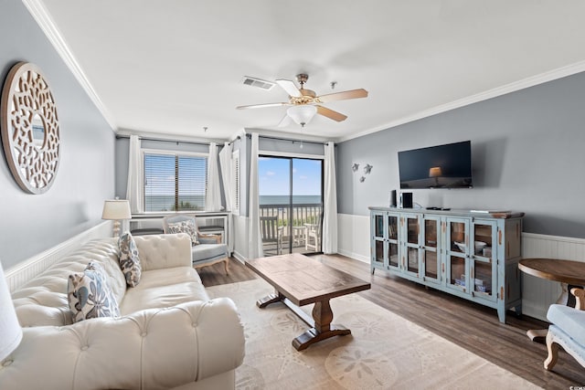 living room featuring ornamental molding, wood finished floors, ceiling fan, and wainscoting
