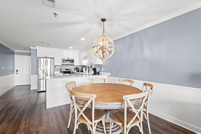 dining area with wainscoting, a chandelier, dark wood finished floors, ornamental molding, and recessed lighting