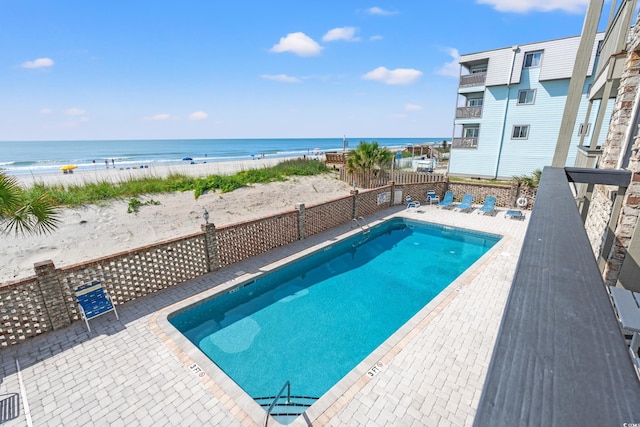 community pool featuring a water view, fence, and a patio