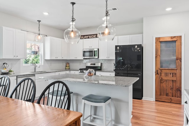205 Marsh Deer Pl, Surfside Beach, SC 29575 - kitchen featuring stainless steel appliances, a sink, a kitchen breakfast bar, tasteful backsplash, and white cabinets