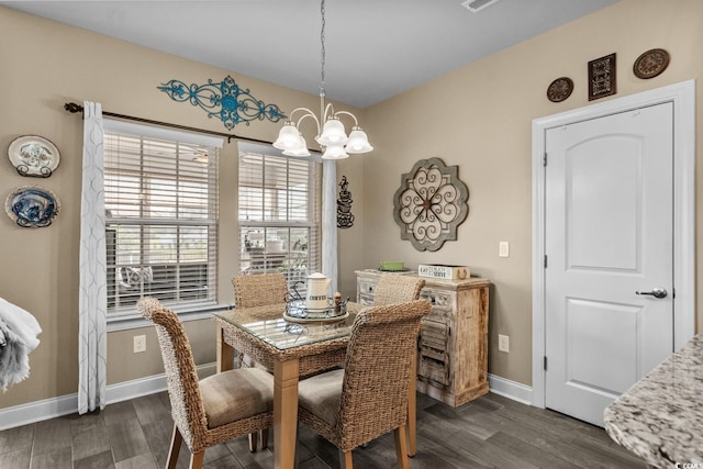 dining room with dark wood-type flooring, a chandelier, and baseboards
