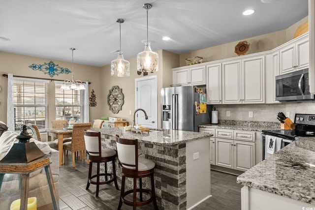 kitchen featuring stainless steel appliances, a sink, white cabinetry, light stone counters, and recessed lighting