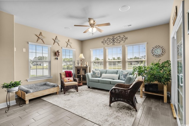 living room featuring a ceiling fan, wood finished floors, and plenty of natural light