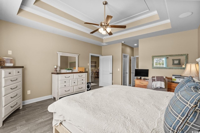 bedroom featuring a raised ceiling, crown molding, wood finished floors, and baseboards