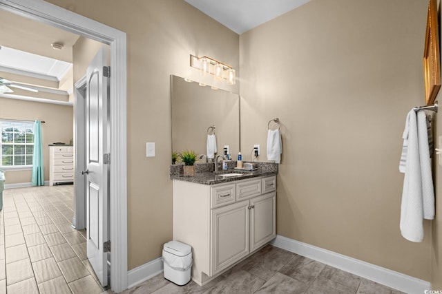 bathroom with baseboards, vanity, a ceiling fan, and a skylight
