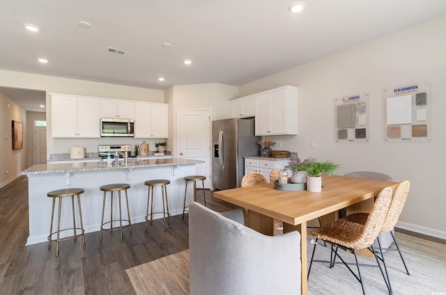 2859 Riverboat Way, Conway, SC 29526 - kitchen featuring appliances with stainless steel finishes, an island with sink, dark wood finished floors, baseboards, and white cabinetry
