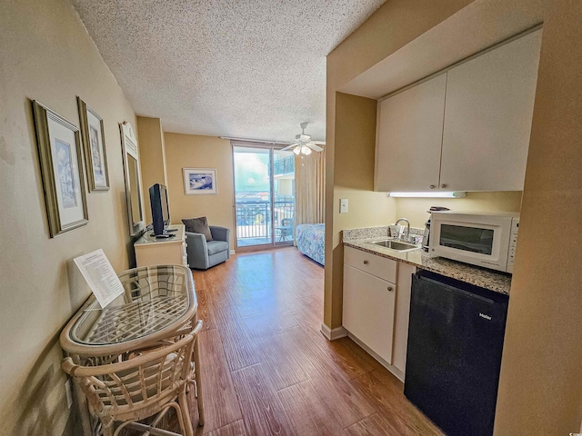 8560 Queensway Blvd Unit 508, Myrtle Beach, SC 29572 - kitchen with white microwave, dishwasher, wood finished floors, a textured ceiling, and a wall of windows