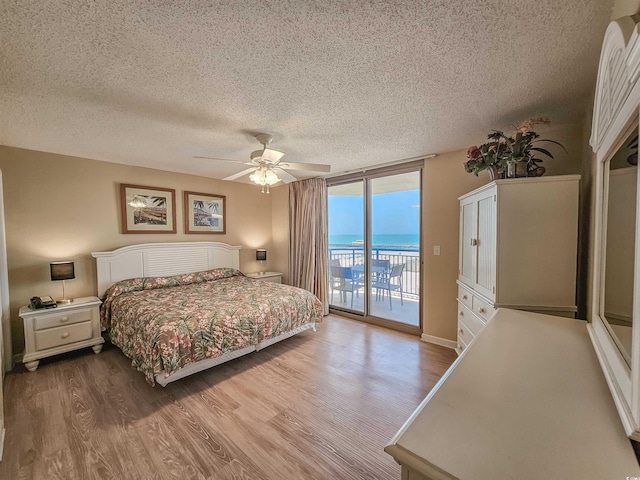 8560 Queensway Blvd Unit 508, Myrtle Beach, SC 29572 - bedroom featuring access to outside, a textured ceiling, wood finished floors, a ceiling fan, and a water view