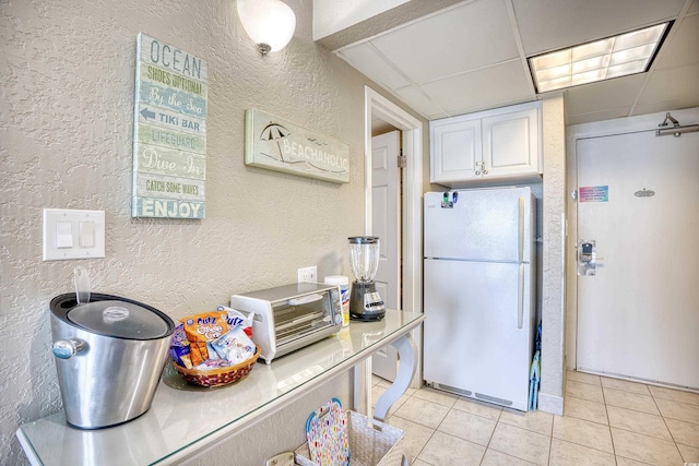 201 74th Ave N Unit 2241, Myrtle Beach, SC 29572 - kitchen featuring freestanding refrigerator, a textured wall, light tile patterned floors, white cabinets, and a paneled ceiling