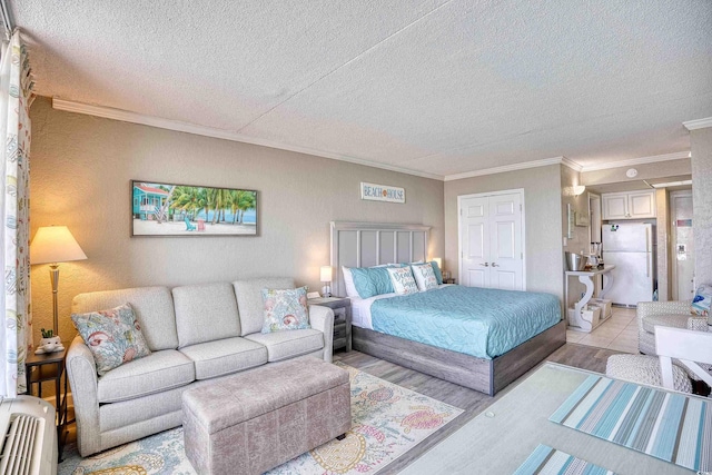 201 74th Ave N Unit 2241, Myrtle Beach, SC 29572 - bedroom featuring freestanding refrigerator, ornamental molding, a textured ceiling, light wood-type flooring, and a closet