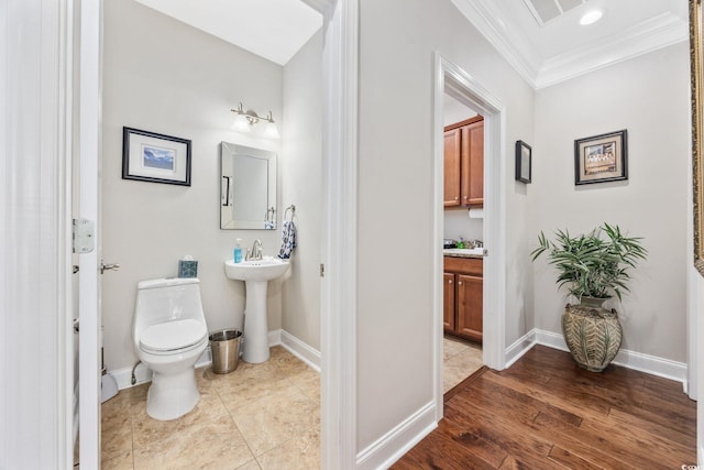 bathroom with ornamental molding, toilet, and baseboards