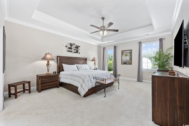 bedroom with a tray ceiling, light colored carpet, ornamental molding, baseboards, and ceiling fan