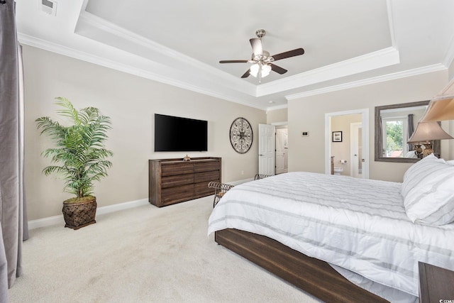 bedroom with a tray ceiling, ornamental molding, carpet flooring, ceiling fan, and connected bathroom