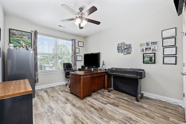 office space featuring baseboards, a ceiling fan, and light wood-style floors