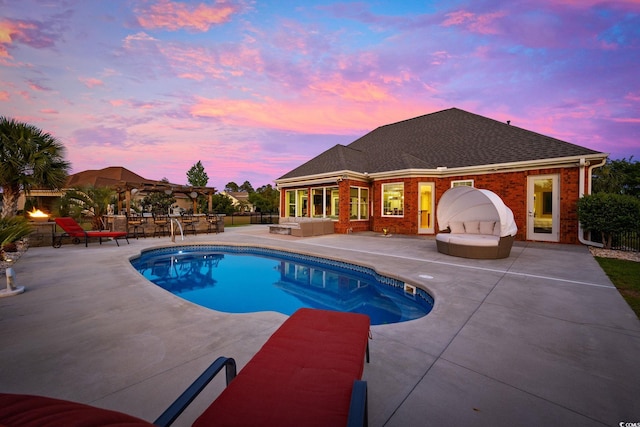 pool at dusk featuring an outdoor hangout area and a patio area
