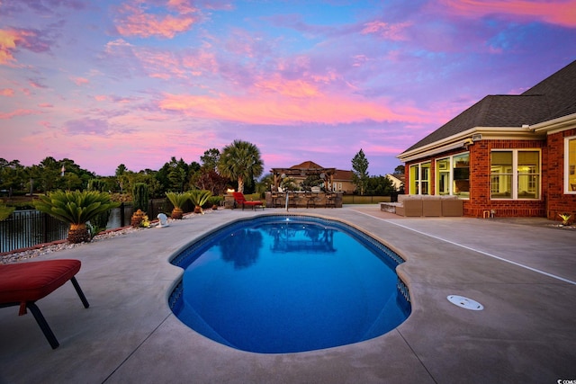 pool at dusk featuring an outdoor hangout area and a patio area