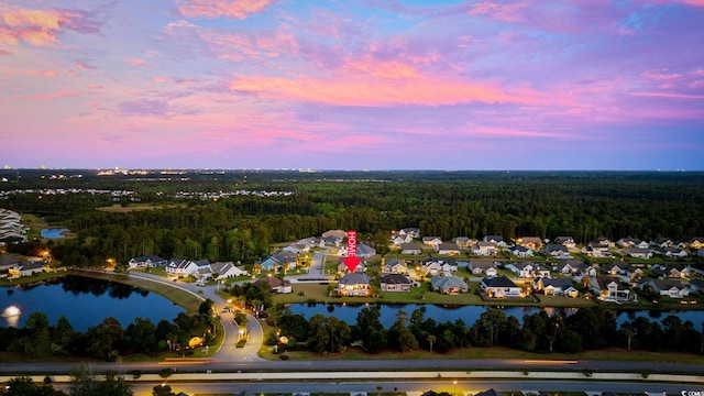 aerial view of property and surrounding area with a forest, a nearby body of water, and nearby suburban area