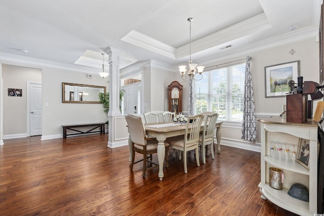 dining room featuring ornamental molding, a tray ceiling, dark wood finished floors, ornate columns, and a chandelier