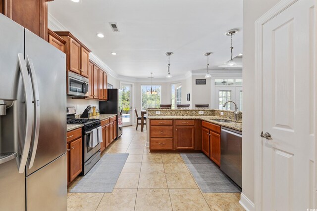 kitchen with appliances with stainless steel finishes, ornamental molding, a sink, brown cabinets, and pendant lighting