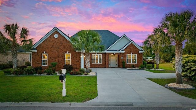 traditional-style home with a yard, brick siding, and driveway