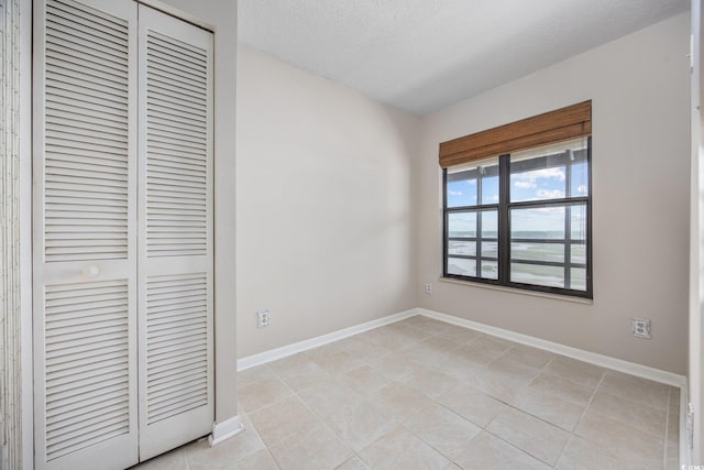 4000 N Ocean Blvd Unit 1002, North Myrtle Beach, SC 29582 - unfurnished bedroom featuring a closet, baseboards, light tile patterned floors, and a textured ceiling
