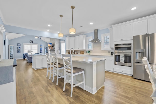 1012 Mary Read Dr, North Myrtle Beach, SC 29582 - kitchen with appliances with stainless steel finishes, wall chimney range hood, open floor plan, light countertops, and white cabinetry