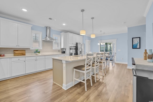 1012 Mary Read Dr, North Myrtle Beach, SC 29582 - kitchen with wall chimney range hood, appliances with stainless steel finishes, light wood finished floors, tasteful backsplash, and white cabinetry