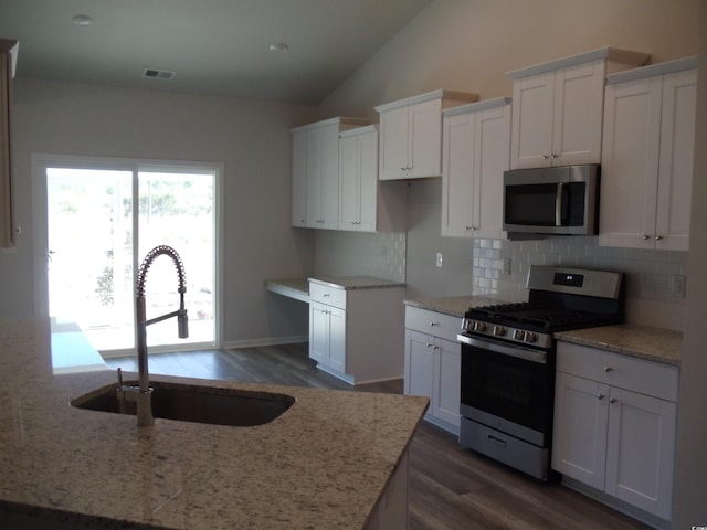 8715 Baton Rouge Ave NW, Calabash, NC 28467 - kitchen featuring stainless steel appliances, a sink, tasteful backsplash, lofted ceiling, and white cabinets
