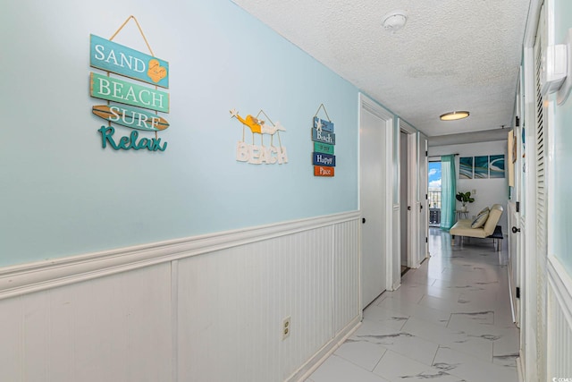 5905 S Kings Hwy Unit 344B, Myrtle Beach, SC 29575 - hallway with light marble finish flooring, a textured ceiling, and wainscoting