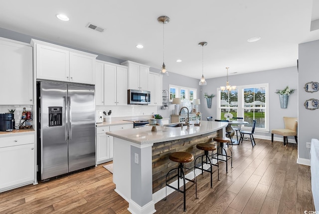 104 Splendor Cir, Murrells Inlet, SC 29576 - kitchen with stainless steel appliances, a sink, light wood-style floors, decorative backsplash, and a kitchen bar