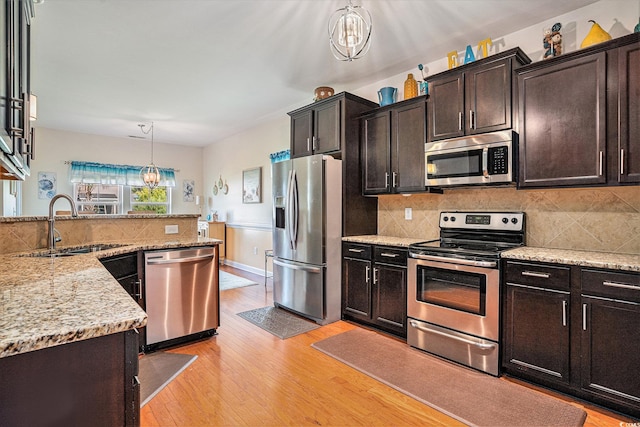 505 Joy Way Ct, Longs, SC 29568 - kitchen with appliances with stainless steel finishes, a sink, light wood-style floors, hanging light fixtures, and decorative backsplash