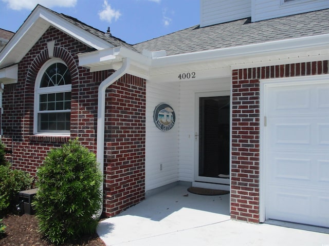 4002 Acorn Way N, Myrtle Beach, SC 29582 - view of exterior entry featuring roof with shingles, brick siding, and a garage