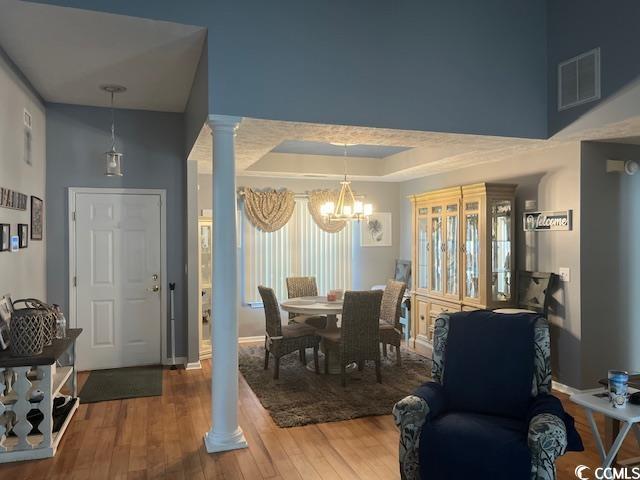 550 Bridgeport Dr, Myrtle Beach, SC 29577 - dining space with decorative columns, a chandelier, baseboards, wood finished floors, and a raised ceiling