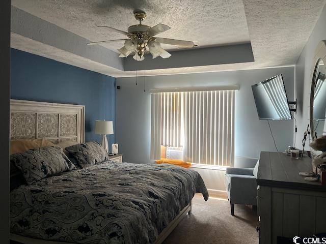 550 Bridgeport Dr, Myrtle Beach, SC 29577 - bedroom featuring a textured ceiling, a raised ceiling, carpet flooring, and a ceiling fan