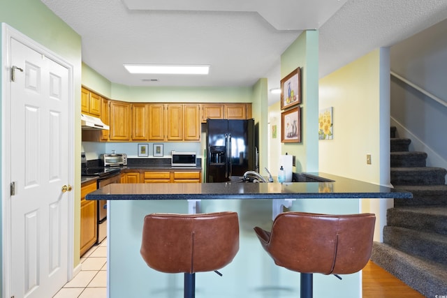 1422 Baldwin Ct Unit 1422, Little River, SC 29566 - kitchen with appliances with stainless steel finishes, under cabinet range hood, a breakfast bar area, dark countertops, and a sink