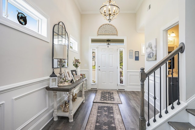 entrance foyer with wood finished floors, stairway, a chandelier, a decorative wall, and a wainscoted wall