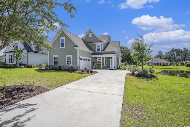 view of front of house with concrete driveway, a water view, a garage, stone siding, and a front yard