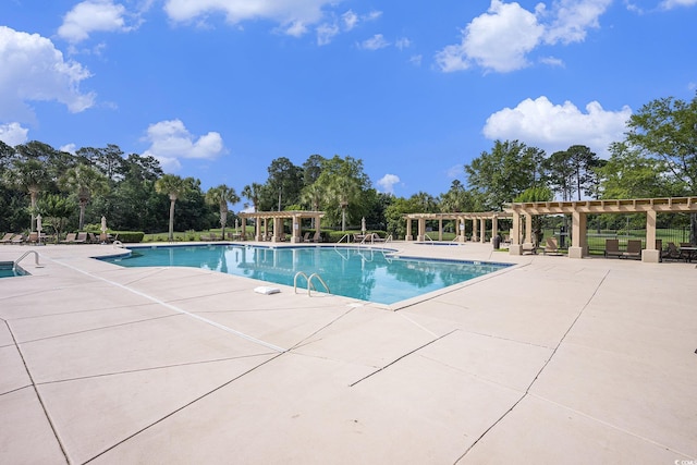 community pool featuring a pergola, a patio area, and view of wooded area