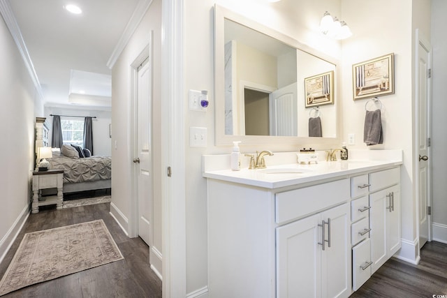 full bathroom with ornamental molding, wood finished floors, ensuite bath, double vanity, and baseboards