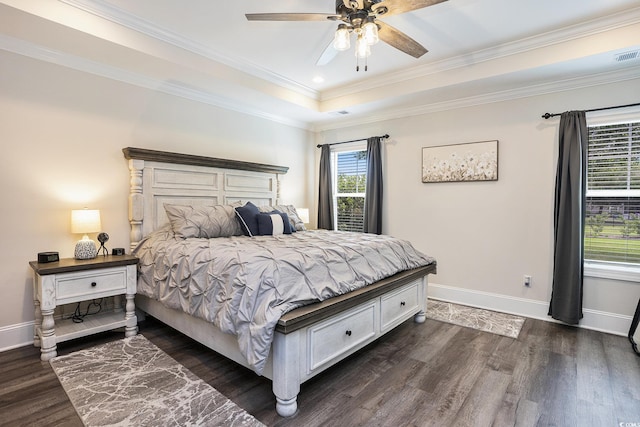 bedroom featuring dark wood-type flooring, ornamental molding, baseboards, a tray ceiling, and ceiling fan