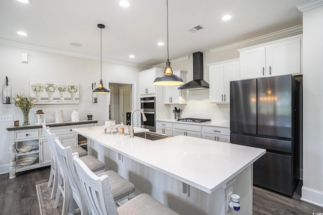 kitchen with wall chimney exhaust hood, stainless steel appliances, dark wood-type flooring, ornamental molding, and white cabinets