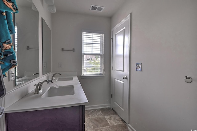 full bathroom featuring baseboards and double vanity