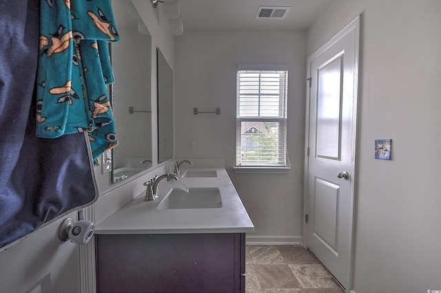bathroom featuring baseboards and double vanity