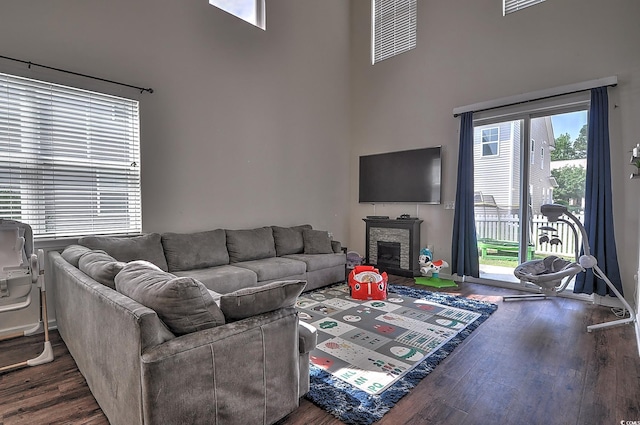 living area with a high ceiling, wood finished floors, and a fireplace