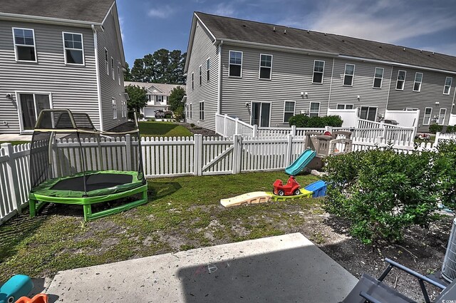 back of house with a trampoline, a fenced backyard, a playground, and a patio