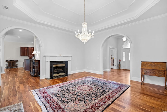 423 Chapman Loop, Pawleys Island, SC 29585 - living area with arched walkways, a chandelier, wood finished floors, a raised ceiling, and a tiled fireplace