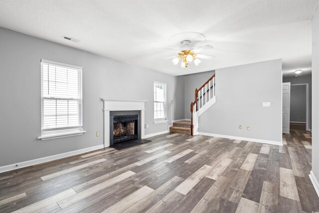 4406 Barcelona Ln, Little River, SC 29566 - unfurnished living room with a ceiling fan, stairway, wood finished floors, a fireplace with flush hearth, and a textured ceiling