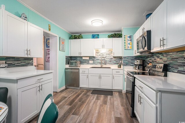 1205 King St, Myrtle Beach, SC 29577 - kitchen with appliances with stainless steel finishes, a sink, crown molding, backsplash, and dark wood-style flooring