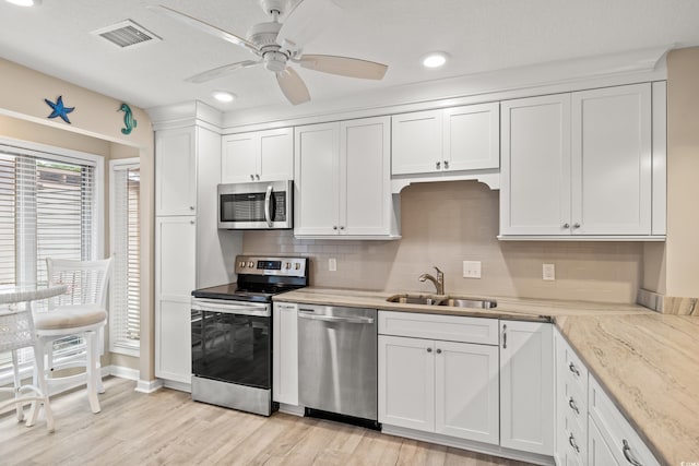 430 Ocean Creek Dr Unit 2534, Myrtle Beach, SC 29572 - kitchen with appliances with stainless steel finishes, a sink, tasteful backsplash, white cabinetry, and light wood-style floors