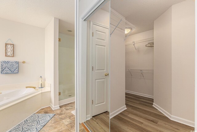 2479 Glen Dr, Little River, SC 29566 - bathroom with a stall shower, a bath, a spacious closet, baseboards, and a textured ceiling